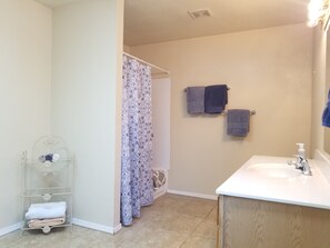 A bathroom with a shower, a sink, and a towel rack.