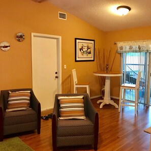 A living room with two armchairs, a small table, a door, and a window with a view. - Nice and quite vacation home (Tampa)