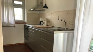 A compact kitchen with a sink, stove, and a window with curtains. - Vacation home 2 - Holiday homes Michaelis 1 to 4 in Quilitz (Rankwitz)