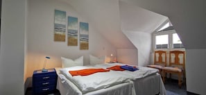 A bedroom with a bed, a desk, a chair, and a window.