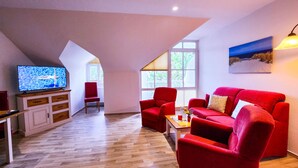 A modern living room with a red sofa, a television, and a wooden cabinet. - 2 Room A 6 - Wohnpark Binz (with indoor pool) (Binz)