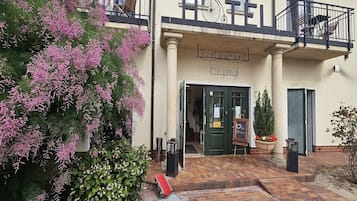 Ein Restaurant mit Balkon, einem Schild über dem Eingang und einem Blumentopf auf dem Boden.
