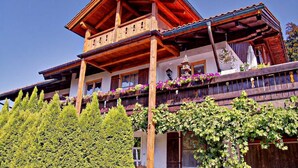 A traditional wooden chalet with a balcony, a bell tower, and a lush garden.