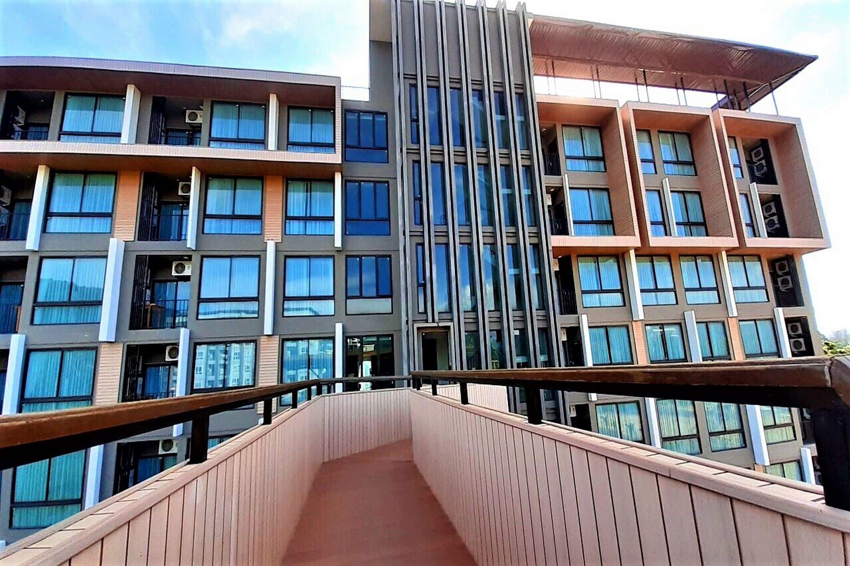 A modern multi-story building with balconies, large windows, and a central atrium.