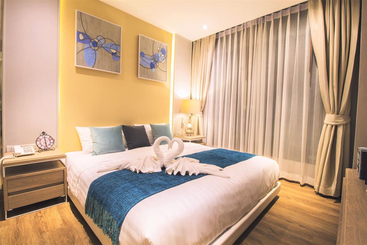 Habitació d'hotel amb un llit gran, una nit pota amb una làmpada i una obra d'art a la paret.