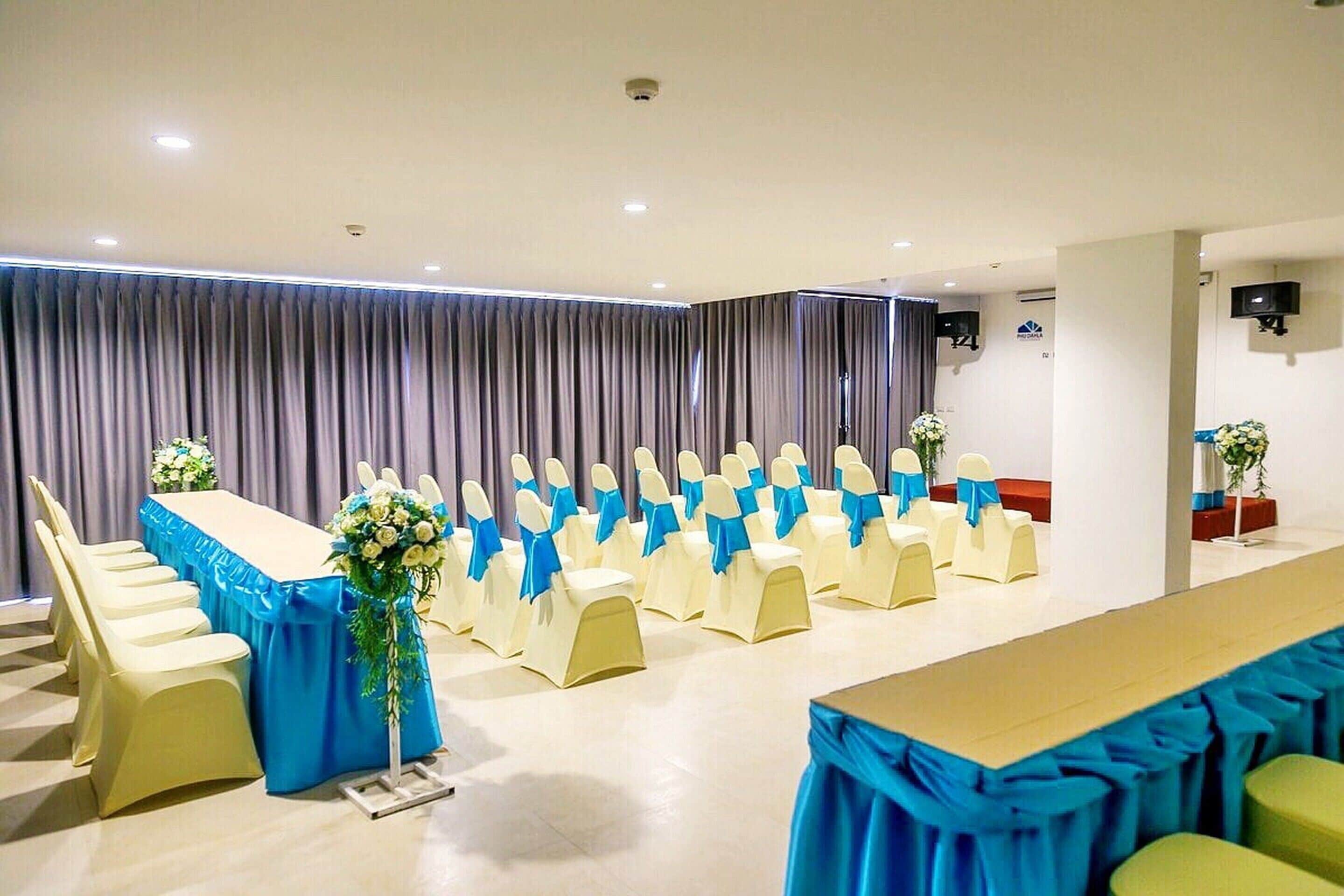 A conference room with rows of chairs, a long table, and a curtain backdrop.