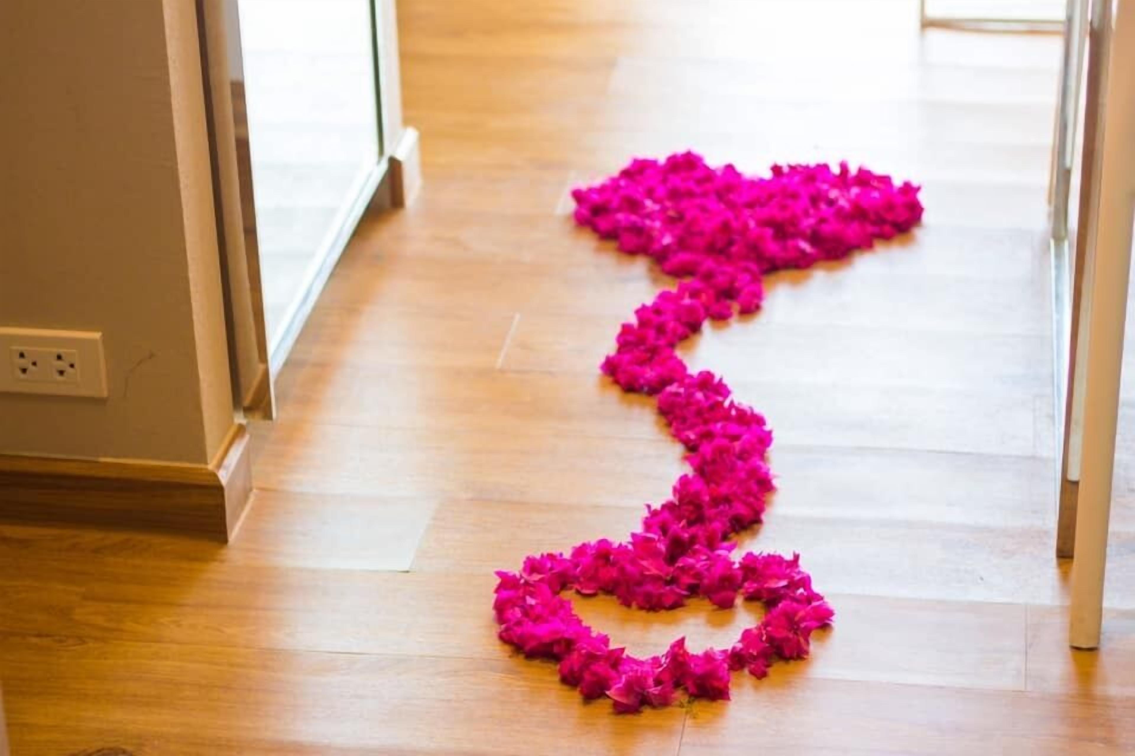 Un suelo de madera con una guirnalda de flores rosas dispuesta en forma de corazón.