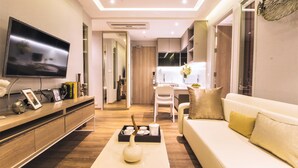 Una sala de estar moderna con un televisor de pantalla plana, un sofá blanco, una mesa de centro y un mueble de madera.