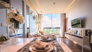 Un comedor moderno con una mesa dispuesta para dos, un florero con flores y vistas al exterior.