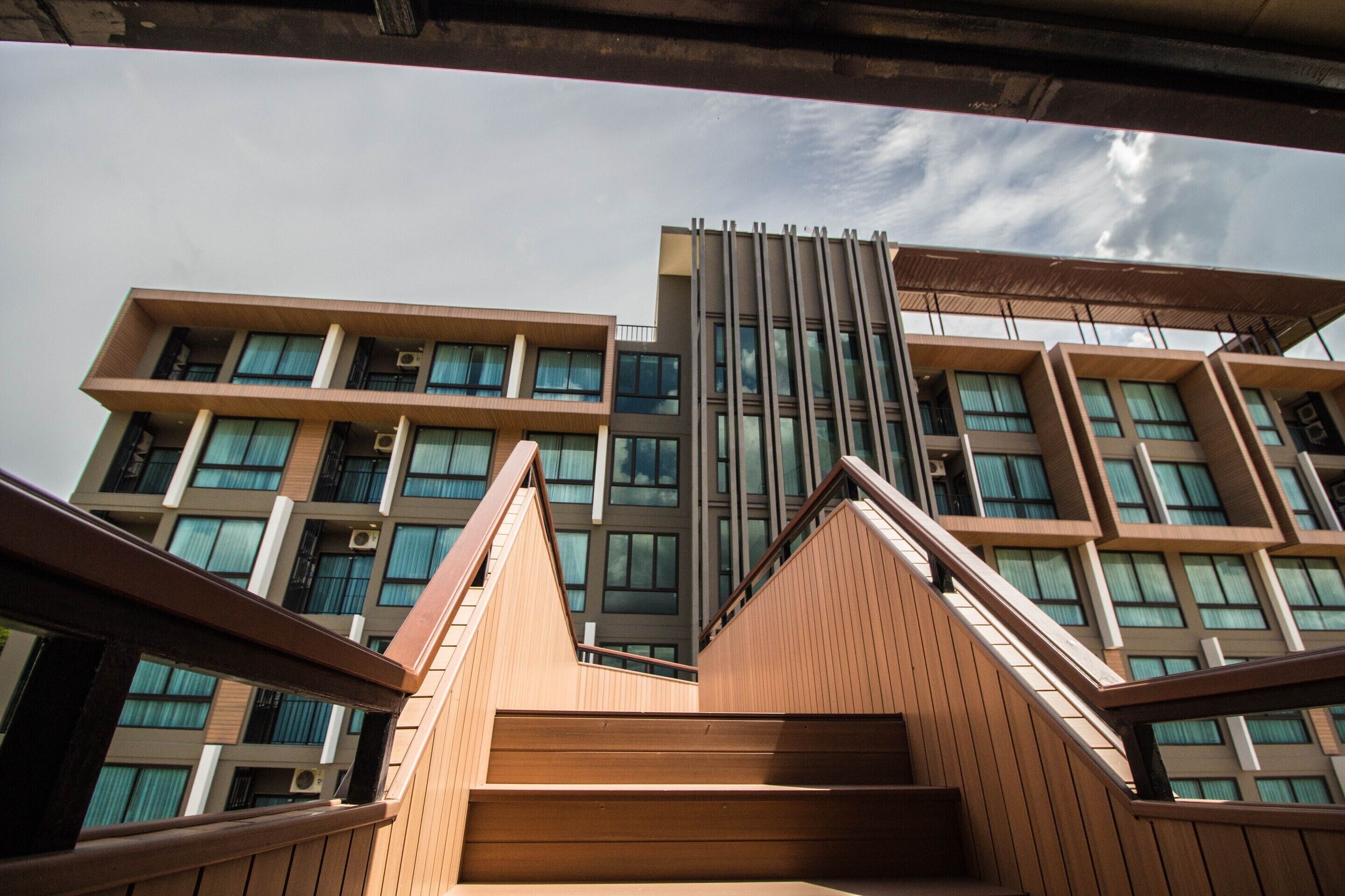 Un immeuble à plusieurs étages doté d’une architecture moderne, avec un escalier central et de nombreux balcons.