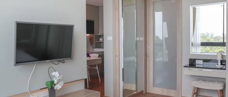 A modern bedroom with a TV, a desk, and a chair, a sliding door, and a window with a view.