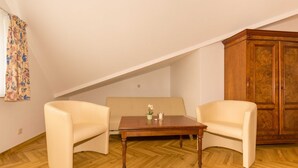 A room with a wooden table, two chairs, a sofa, and a wooden cabinet.