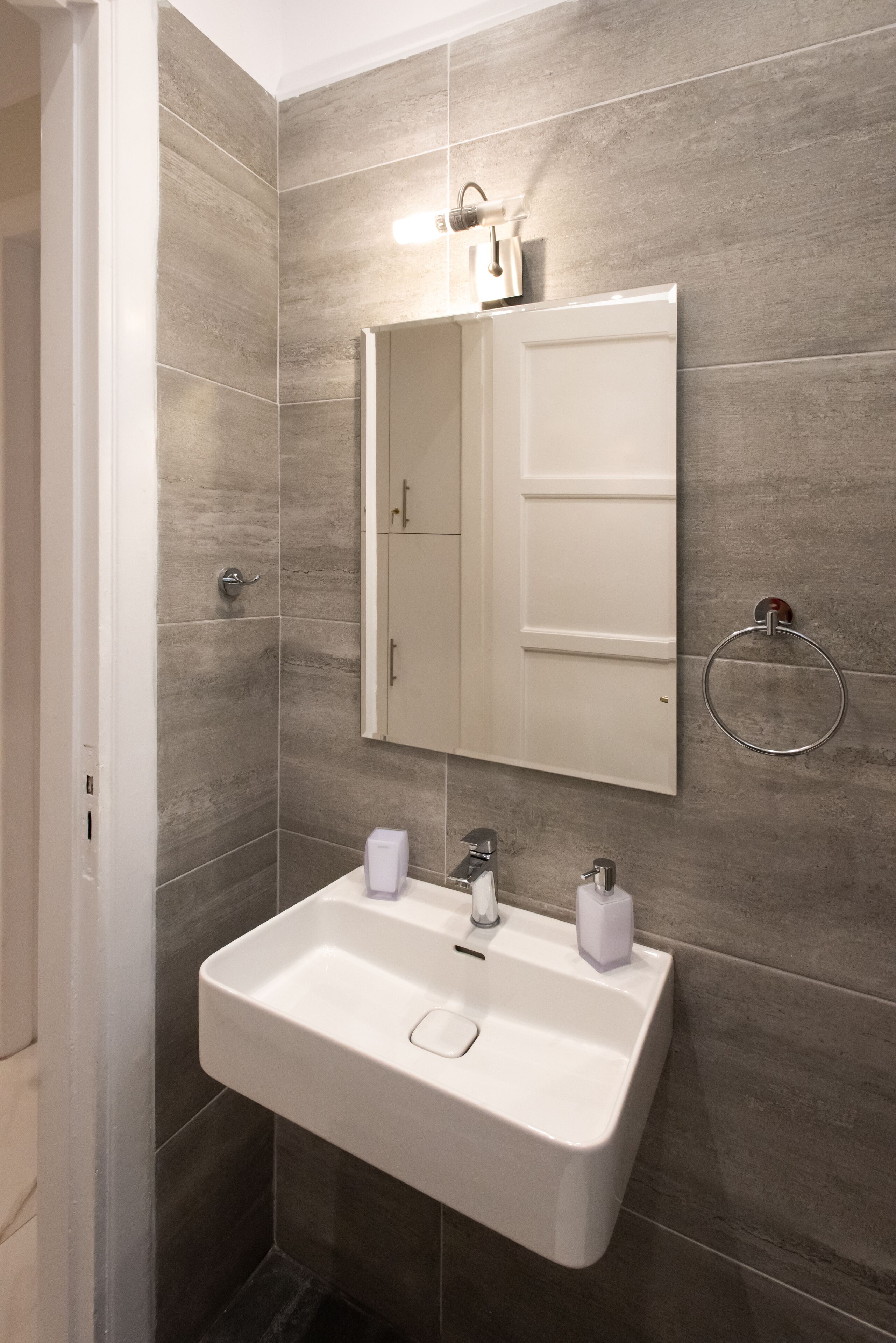 A bathroom with a white sink, a mirror, and a towel ring.