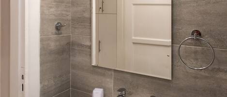 A bathroom with a white sink, a mirror, and a towel ring.