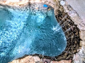 Une piscine à l’eau claire, entourée de murs de pierre et bordée de rochers.