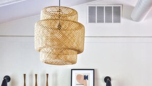 Un espace repas moderne avec une table en marbre, des chaises en métal, un luminaire suspendu en fibres tressées et un banc en bois.
