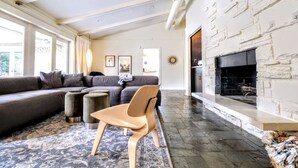 Un salon moderne avec un canapé d’angle, une cheminée et une grande fenêtre.