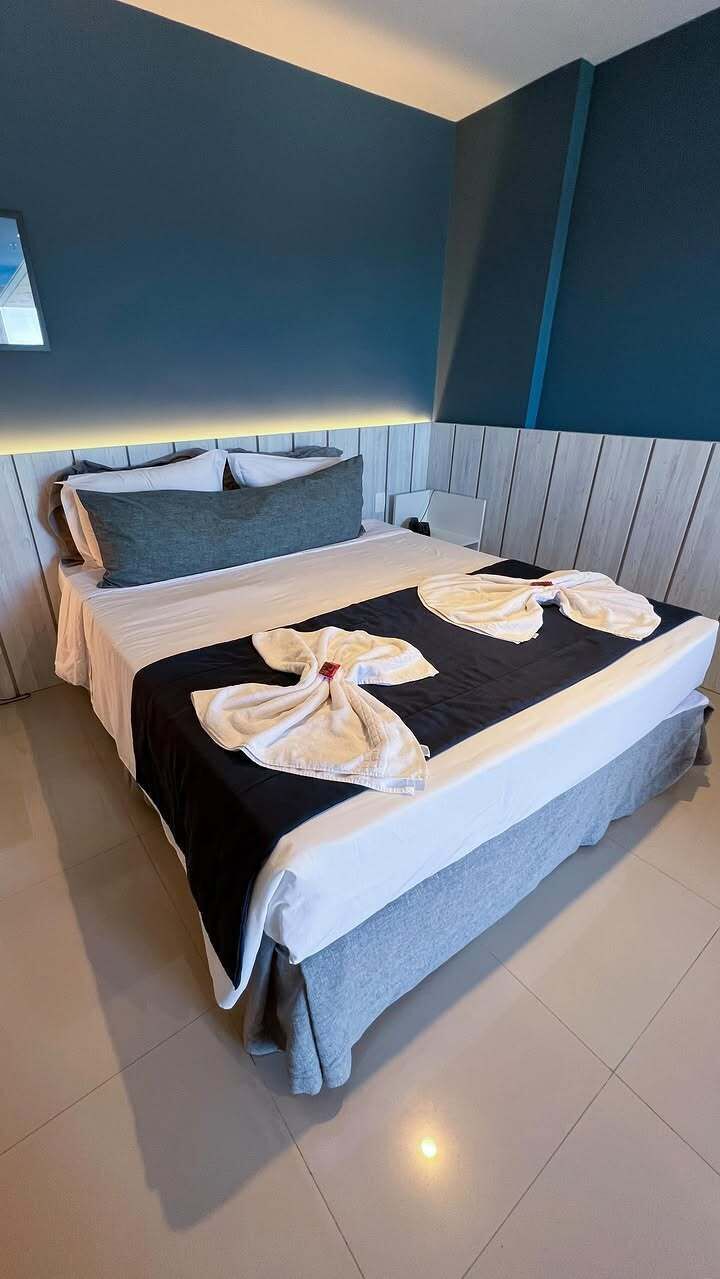 A neatly made bed with a black and white bedspread, pillows, and a towel arrangement.