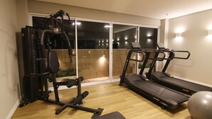 Ein Heim-Fitnessraum mit Laufband, Ergometer und Gewichten.