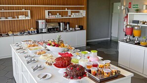 Ein Buffet mit verschiedenen Speisen und Getränken, eine Kaffeestation und ein Feuerlöscher an der Wand.