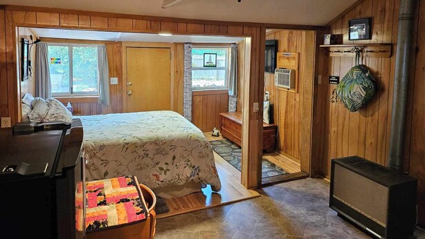 A cozy room with a bed, a desk, a heater, and a window with curtains. - Cozy studio cabin close to Lake Michigan. (Frankfort)