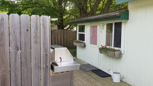 A wooden deck with a grill, a white shed with flower boxes, and a white bucket. - Cozy studio cabin close to Lake Michigan. (Frankfort)