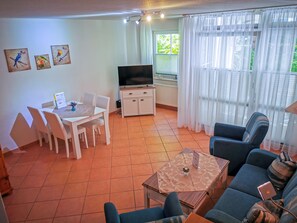 Un salon comprenant un téléviseur, une table à manger, des chaises et un canapé.