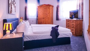 A hotel room with a bed, a wooden wardrobe, a television, and a lamp. - 2 Room C 7 - Wohnpark Binz (with indoor pool) (Binz)