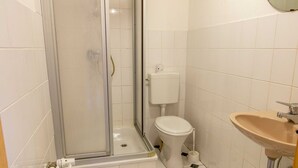 A bathroom with a glass-enclosed shower, a toilet, and a sink. - Single Room (21) - Pension Zur Curve (Prohn)