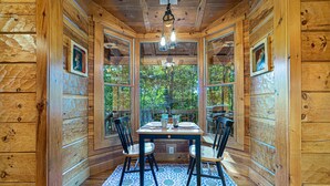 A wooden cabin with a dining area featuring a table, chairs, and a patterned rug. - Luxury cabin in the woods, 2 bedrooms plus loft (Fairfield)