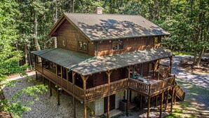 A two-story wooden cabin with a balcony and deck, surrounded by trees. - Luxury cabin in the woods, 2 bedrooms plus loft (Fairfield)