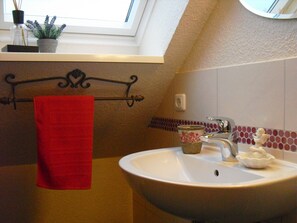 A bathroom with a skylight, a red towel, a sink, and a decorative vase. - Bauernhof Serck (Fehmarn)