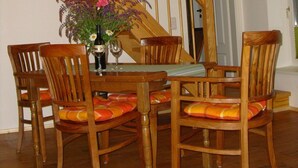 Une table à manger en bois, des chaises, un vase avec des fleurs et un escalier avec des poutres en bois.