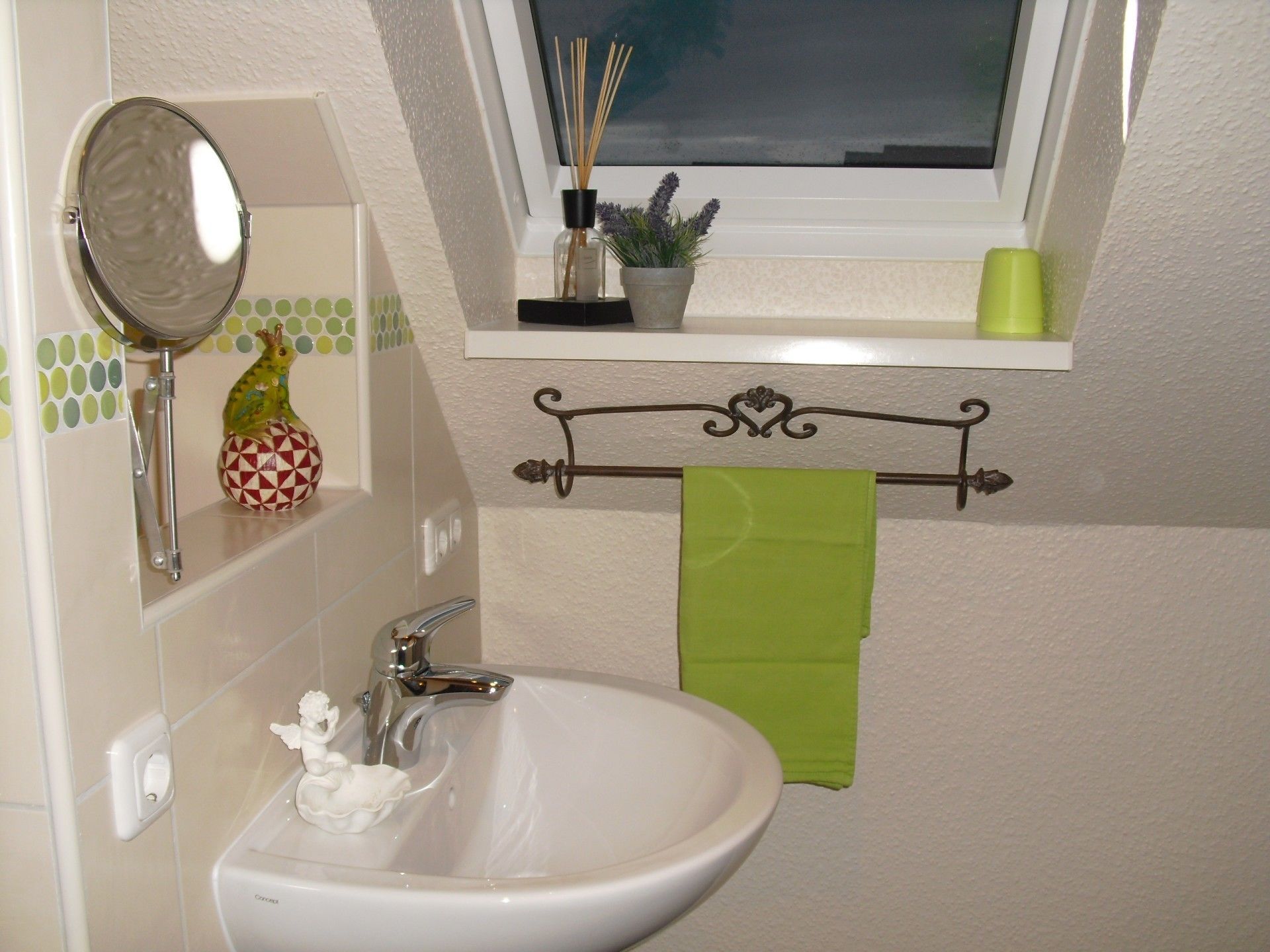 A bathroom with a white sink, a mirror, a window with a view, and a shelf with a plant and candles.