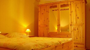 Une chambre à coucher avec un lit en bois, une table de chevet avec une lampe et une armoire en bois.
