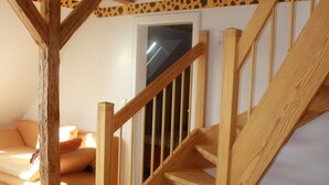 Un escalier en bois dans une pièce dont le sol et le canapé sont également en bois.
