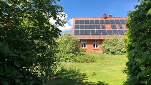 A house with solar panels on the roof, surrounded by greenery and a well-maintained lawn. - Vacation home 3 - Holiday homes Michaelis 1 to 4 in Quilitz (Rankwitz)
