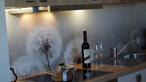 A kitchen with a modern stove, a wine bottle, and two glasses on the counter. - Haus an der Pferdekoppel (Fehmarn)