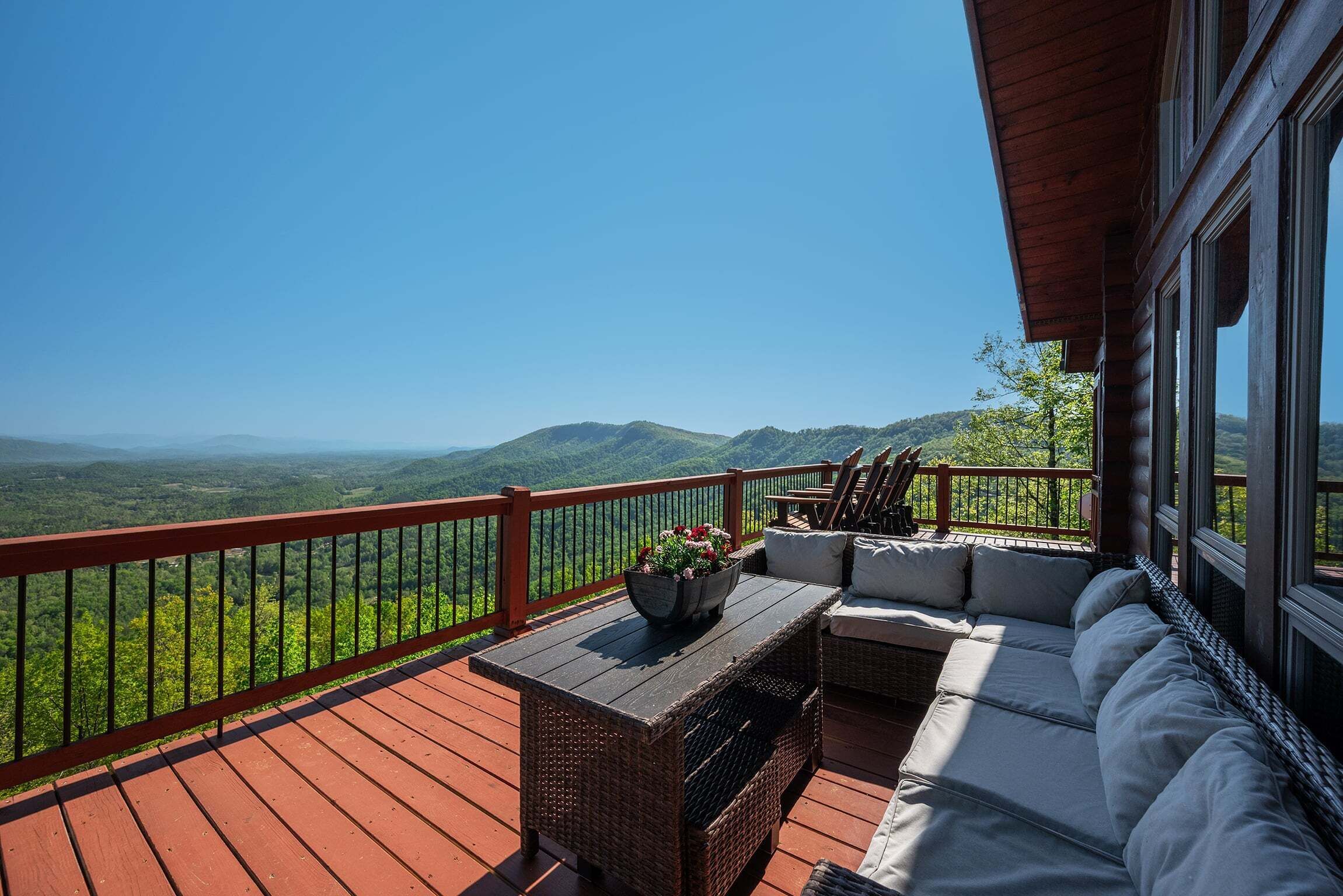 Une terrasse avec un canapé, une table et un pot de fleurs.
