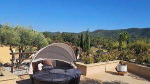 A wicker chair with a canopy, a potted plant, and a view of a mountainous landscape. - Beautiful villa with two swimming pools—one outdoor and one indoor—and a Jacuzzi (Hérépian)