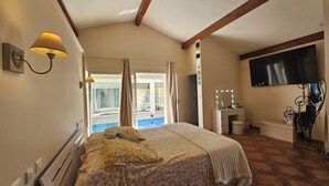 A bedroom with a bed, a vanity with a mirror, and a television on the wall. - Beautiful villa with two swimming pools—one outdoor and one indoor—and a Jacuzzi (Hérépian)
