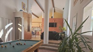 A pool table in a room with a kitchen area visible through an open door. - Beautiful villa with two swimming pools—one outdoor and one indoor—and a Jacuzzi (Hérépian)