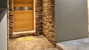 Eine Hausecke mit Holztür, Steinmauer und einer Lampe.