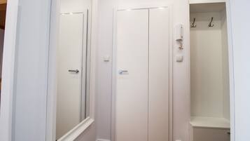 Un interior blanco con una puerta, un interruptor de luz y un estante pequeño con ganchos.
