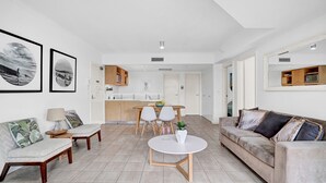 A modern living room with a sofa, a coffee table, and a dining area with chairs.