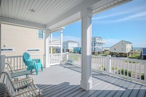 A covered porch with a view of neighboring houses and the ocean. - Sea Glass: Beautiful, Spacious, Beachfront House on East Beach (Oak Island)