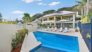 Une maison moderne à deux étages, dotée d’une piscine, d’un espace de détente extérieur et offrant une vue sur les collines environnantes.