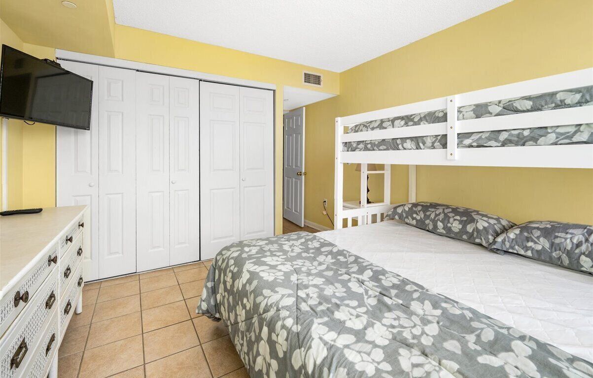 A bedroom with a bunk bed, a dresser, a TV, and a wardrobe.