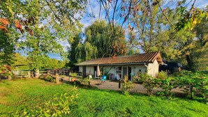 Een rustiek huis met pannendak, omgeven door weelderige begroeiing en bomen.