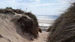 A sandy beach path with dunes and a view of the ocean.